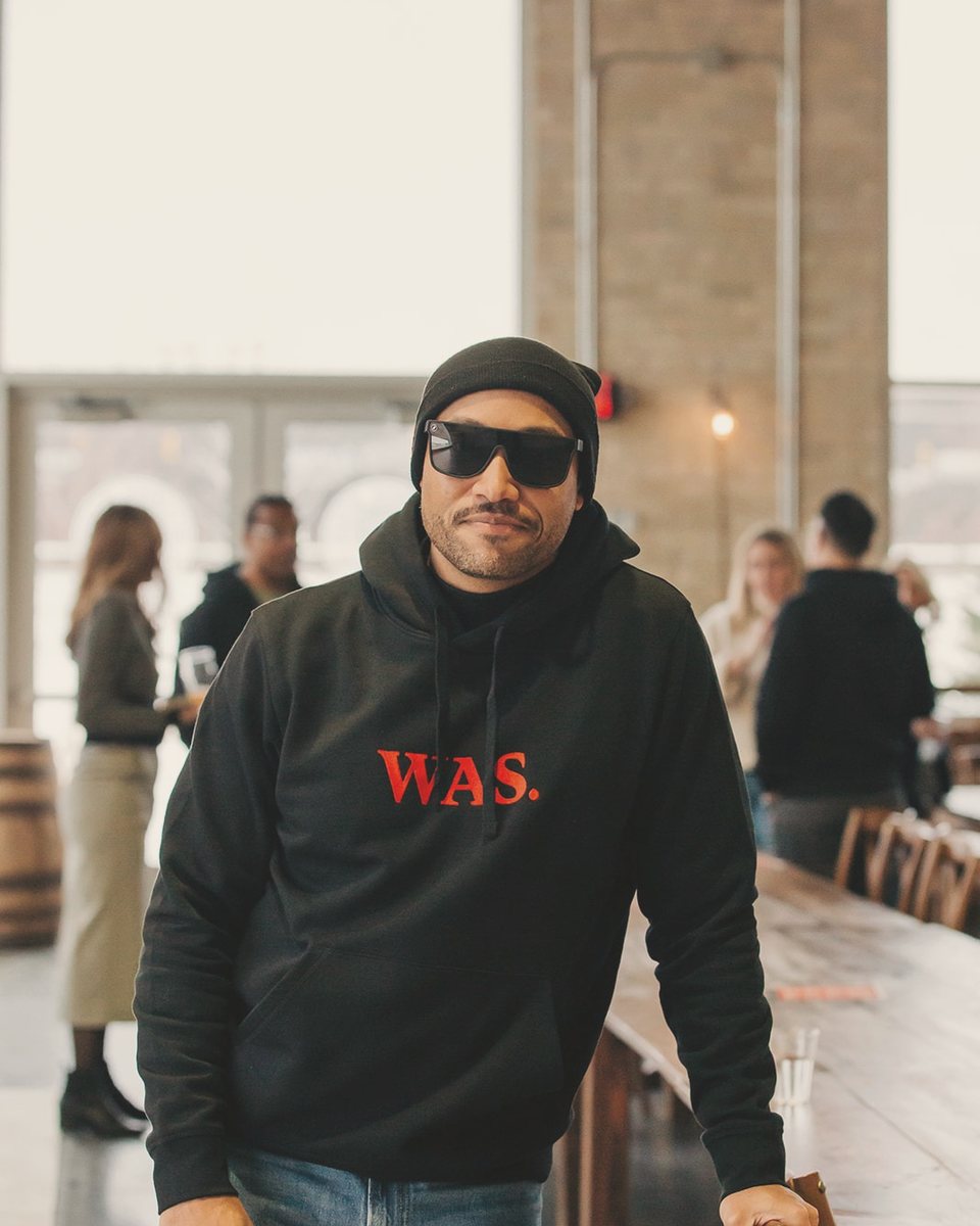Jarrett Reed in a black hoodie and sunglasses, leaning on a long table in a bright room.